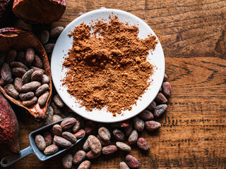 Top view of Natural cocoa powder with brown cocoa beans and dry cacao pod  on a vintage wooden table.