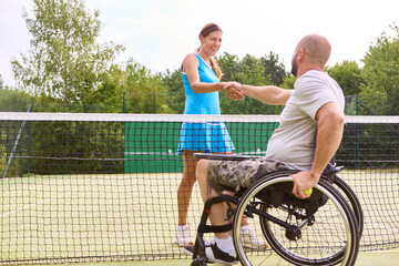Positive interaction at the tennis court with an athletic person in a wheelchair and a standing...