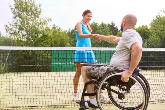 Positive interaction at the tennis court with an athletic person in a wheelchair and a standing partner