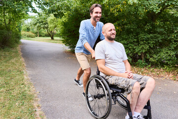 Smiling man using a wheelchair enjoying a day at the park with a friend