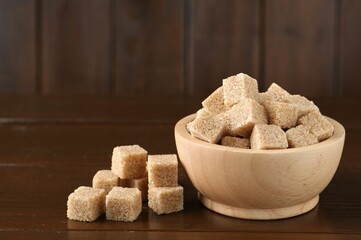 Brown sugar cubes on wooden table, closeup