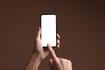 Man using smartphone with blank screen on brown background, closeup. Mockup for design