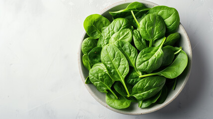 Fresh green spinach leaves in a ceramic bowl on a white background.