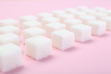 White sugar cubes on pink background, closeup
