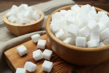 Fototapeta na wymiar White sugar cubes on wooden table, closeup