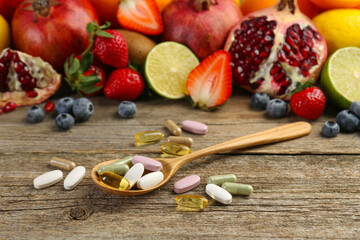 Different vitamin pills and fresh fruits on wooden table
