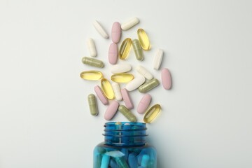 Vitamin pills and bottle on light background, top view