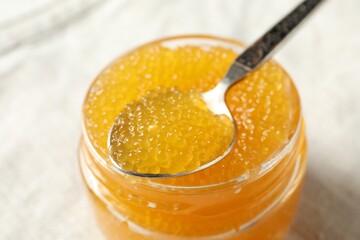 Fresh pike caviar in glass jar and spoon on table, closeup