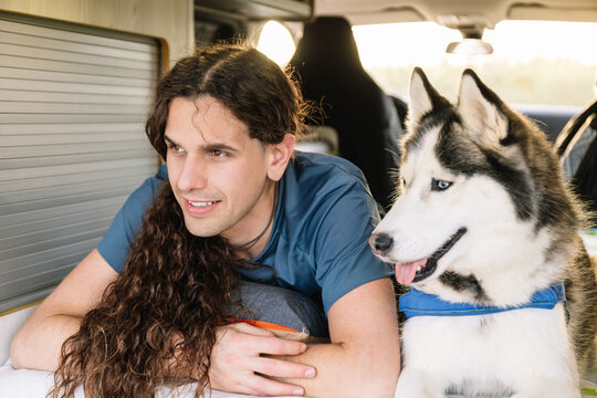 Horizontal photo man and husky enjoying downtime in their camper. Lifestyle concept.