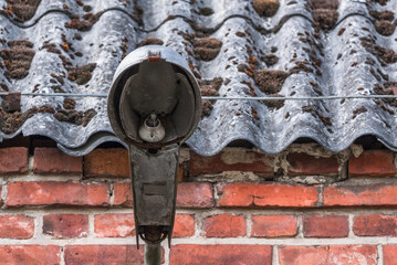 STREET LAMP - Very old and destroyed lantern on an old brick building with an asbestos roof
