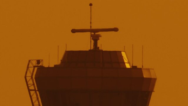 extreme close up of Air traffic control tower in airport at sunset with orange sky 