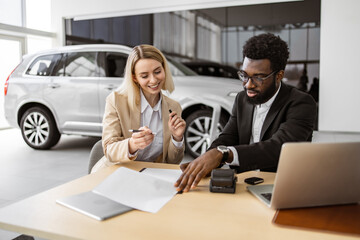 Caucasian rich woman customer buyer client in suit sign paper contract document with African...