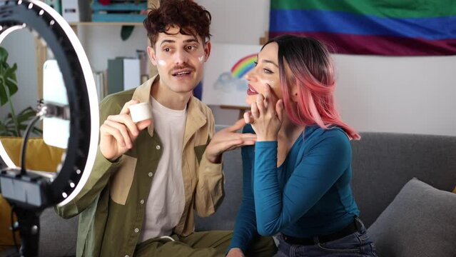 A male and female beauty influencer share skincare tips during a video shoot, capturing a candid moment of fun and education. Beauty Bloggers Demonstrating Skincare Routine on Camera