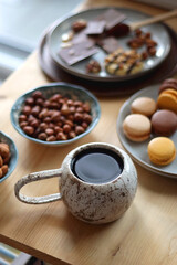 Obraz na płótnie Canvas Cup of tea or coffee, cookies, macaroons, chocolate, various nuts and cocoa powder on wooden table. Selective focus.