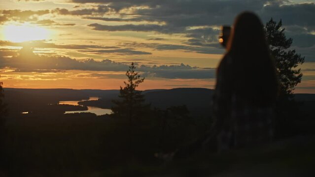 Finland, Rovaniemi. Magnificent view from King's lean-to on the top of Santavaara hill. Silhouette of a female with a phone. A wonderful sunset in the summer evening. Tourism, hiking, Lapland sights