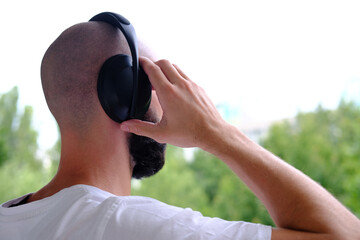 closeup young charismatic man, bearded guy in black headphones listens to music against natural background, Melodies in nature, Sound of solitude