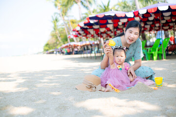 Mother and girl playing in the sand on the beach, Pattaya, Thailand,Mother with children playing with sand on beach 
