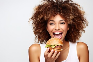 Woman enjoying a hamburger, cheerful with curly hair against white background