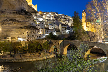 Alcalá del Júcar at night, located on a rock formed by the gorge of the Júcar River, cave houses...