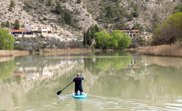 Man doing paddle surfing in Jucar River through the Tolosa Bridge, Tolosa, Alcal&aacute; del J&uacute;car, in the province of Albacete, autonomous community of Castilla-La Mancha