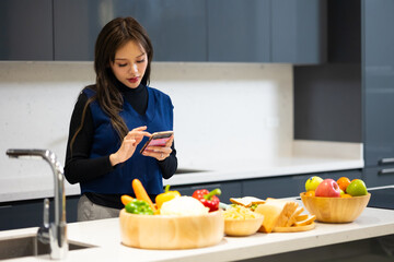 Happy woman relaxing at home - young Asian woman Relaxed and taking online courses for preparation dinner with organic fresh meal.