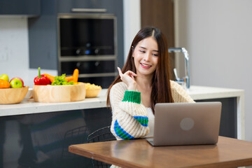 Happy woman relaxing at home - young Asian woman Relaxed working with computer at home. remote working from home office during quarantine