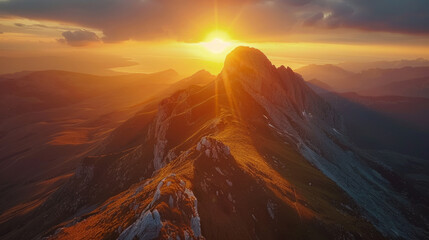 A majestic aerial view of a remote mountain range during golden sunset, highlighting the beauty of nature's wilderness.