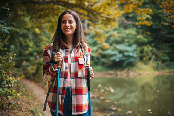 Happy woman with a backpack spending a day in nature, a portrait. Young woman hiking and going camping in nature. Person with backpack walking in the forest - 786263490