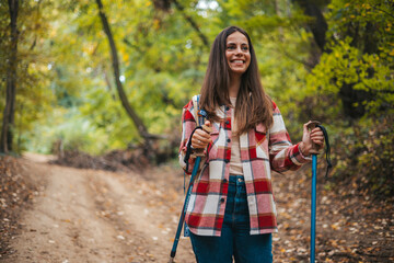 Photo of a young smiling woman carrying a backpack and hiking in the nature. Young woman breathing pure air in a forest. Happy hiker caucasian woman smile and enjoy the nature walking - 786263882