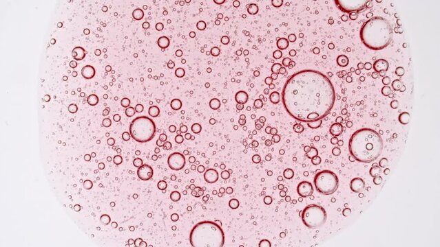 Transparent pink cosmetic gel fluid with molecule bubbles oil distribution on a white background. Macro Shot of Natural Organic Cosmetics, Medicine. Production Close-up. Slow Motion. High quality 4k