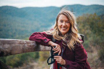Hiker portrait. Female hiking woman happy and smiling during hike trek. Beautiful young Caucasian sporty model joyful. Portrait of a happy woman hiker standing on the slope of mountain