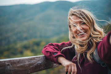 Young woman taking selfie portrait hiking mountains. Happy hiker on the top of the cliff smiling at...