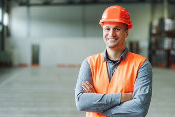Handsome foreman, construction wearing workwear and hard hat, looking at camera with crossed arms