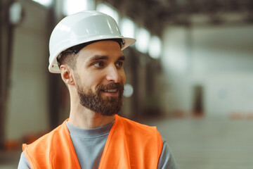 Handsome bearded Caucasian man, professional foreman, architect wearing hard hat and workwear