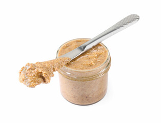 Delicious nut butter in jar and knife isolated on white