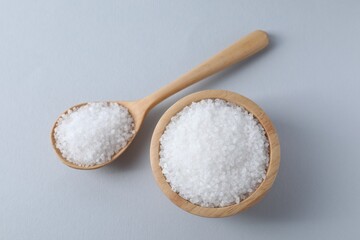 Fototapeta na wymiar Organic white salt in bowl and spoon on light grey background, top view