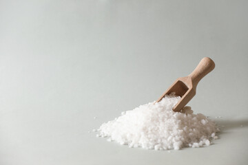 Organic salt and wooden scoop on light grey background. Space for text