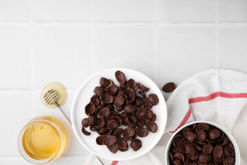 Breakfast cereal. Chocolate corn flakes and milk in bowl on white tiled table, flat lay. Space for...