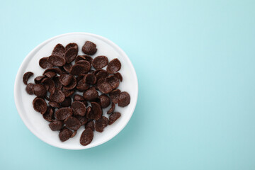 Breakfast cereal. Chocolate corn flakes and milk in bowl on turquoise background, top view. Space for text