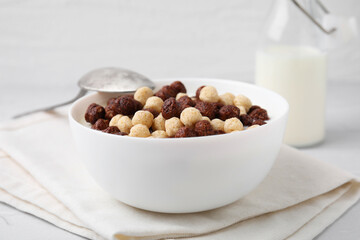 Breakfast cereal. Tasty corn balls with milk in bowl and spoon on table, closeup