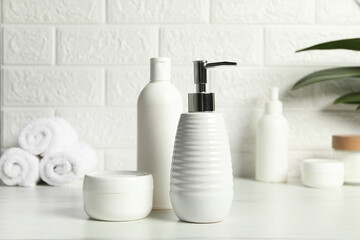 Different bath accessories and personal care products on white table near brick wall