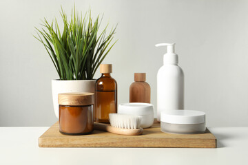 Different bath accessories and houseplant on white table against grey background