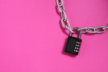 Steel combination padlock and chain on pink background, top view. Space for text