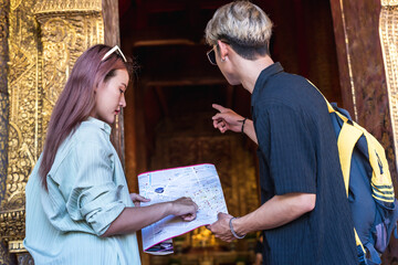 Young Asian tourist couples looking at city map finding direction during summer vacation