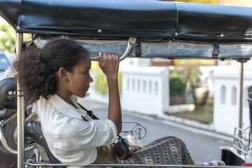 Happy black tourist woman sitting in local tuktuk exploring Thailand during summer vacation - obrazy, fototapety, plakaty