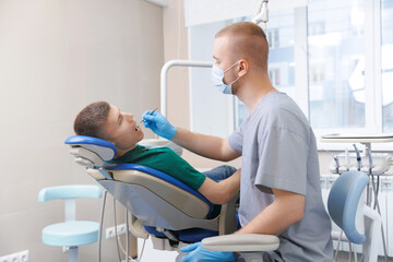 Dentist examining man patient teeth in dentist clinic.