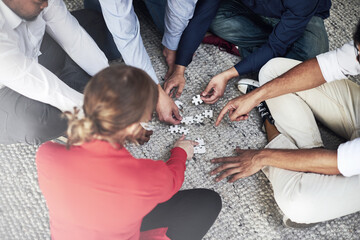 Business, people and hands with puzzle on floor for team building, common goal and problem solving...