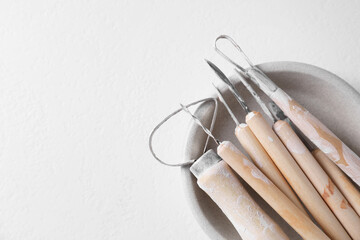 Set of different clay crafting tools on white table, top view. Space for text