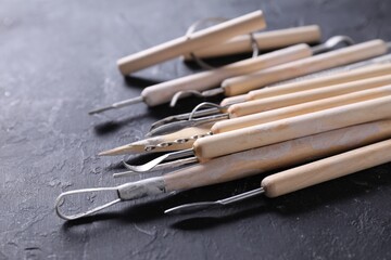 Set of different clay crafting tools on black table, closeup