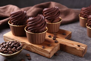 Delicious chocolate cupcakes and coffee beans on grey textured table, closeup
